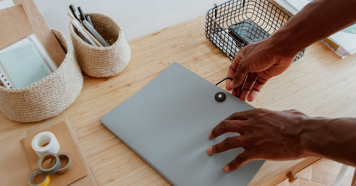 Office desk setup with hands organizing documents, supplies, and technology essentials.