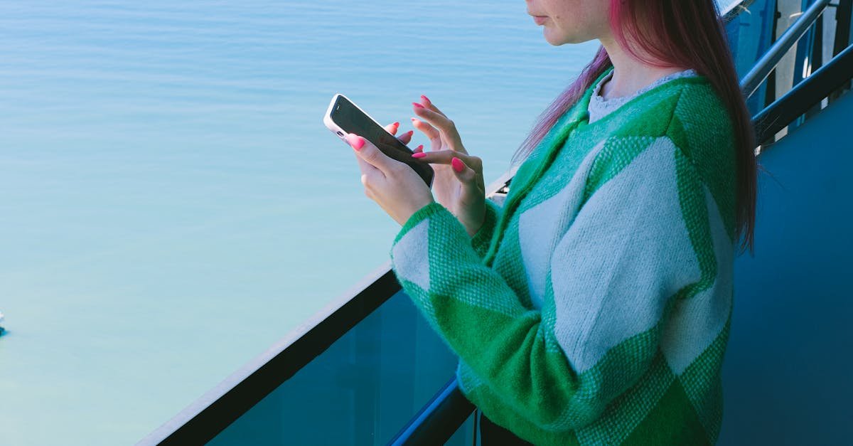 Woman using a smartphone on a balcony with a tranquil ocean view.