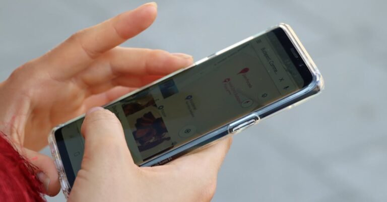 Hands holding a smartphone with a clear case, browsing a map outdoors.