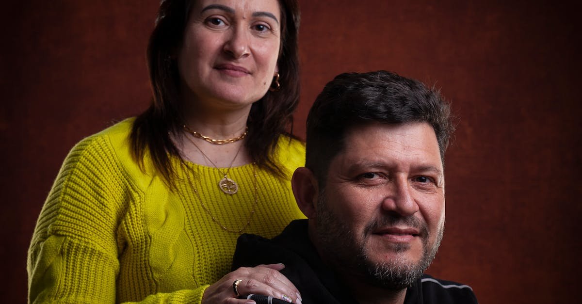 Smiling couple posing in a studio with warm lighting and a dark background.