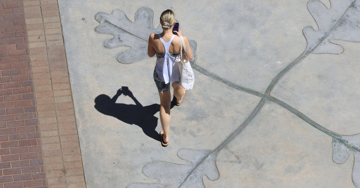 Aerial view of a woman walking with phone on decorative leaf motif pavement in an urban setting.