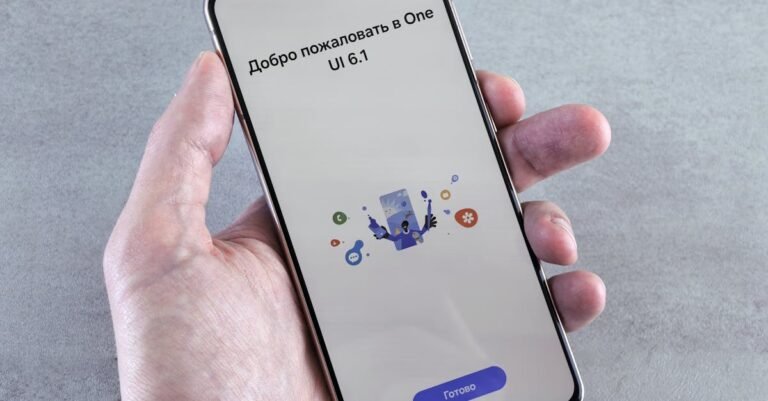 A close-up of a hand holding a smartphone displaying One UI 6.1 setup screen with Cyrillic text.