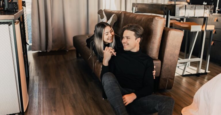A joyful couple sharing a tender moment on the floor by the sofa in a cozy living room.