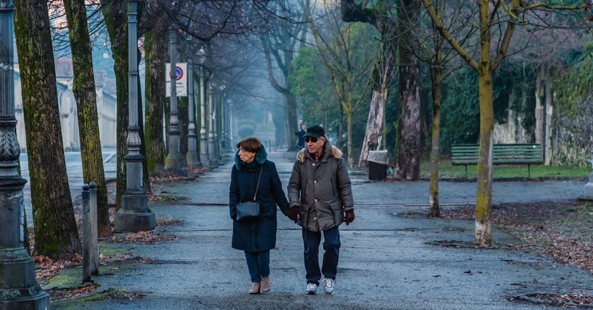 Elderly couple strolls hand in hand through a serene park in Italy, capturing a moment of togetherness.