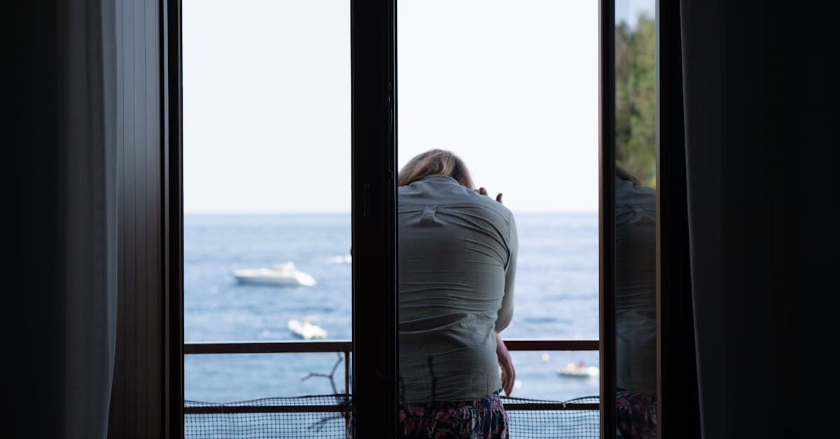 A woman sits thoughtfully on a balcony overlooking the serene Campania sea, Italy.