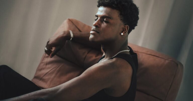 Relaxed young man sitting on a chair indoors in a thoughtful pose.