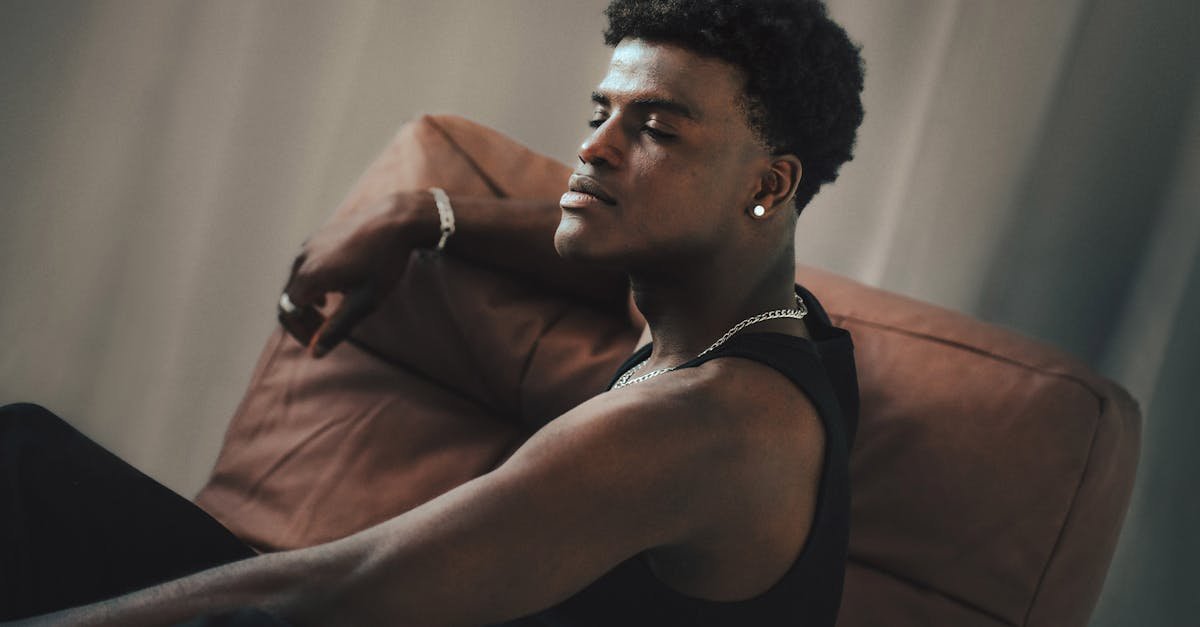 Relaxed young man sitting on a chair indoors in a thoughtful pose.