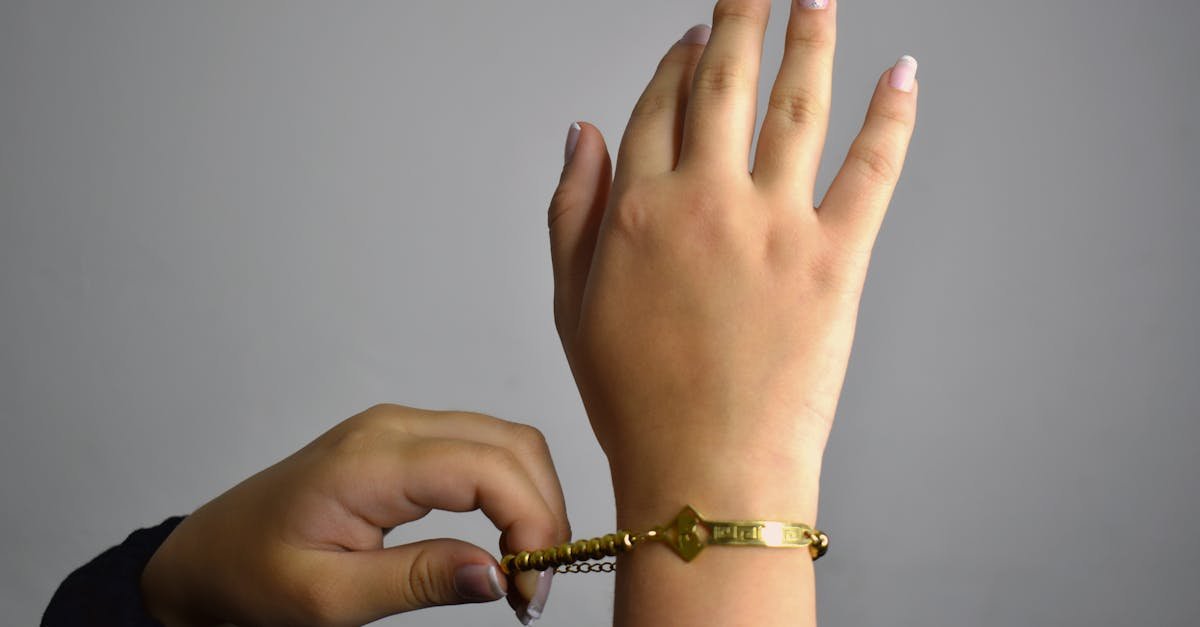A detailed view of hands adjusting a gold bracelet, showcasing jewelry style.