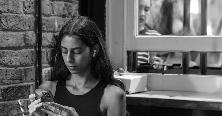 A young woman focused on her smartphone indoors, expressing modern lifestyle.