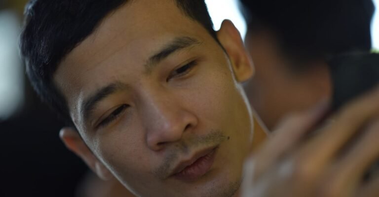 A focused man engaging with his smartphone in a casual indoor setting.