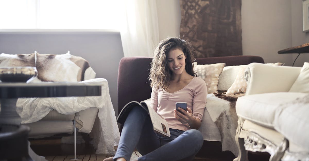 Young woman relaxing in a stylish living room, reading a magazine and using her phone.