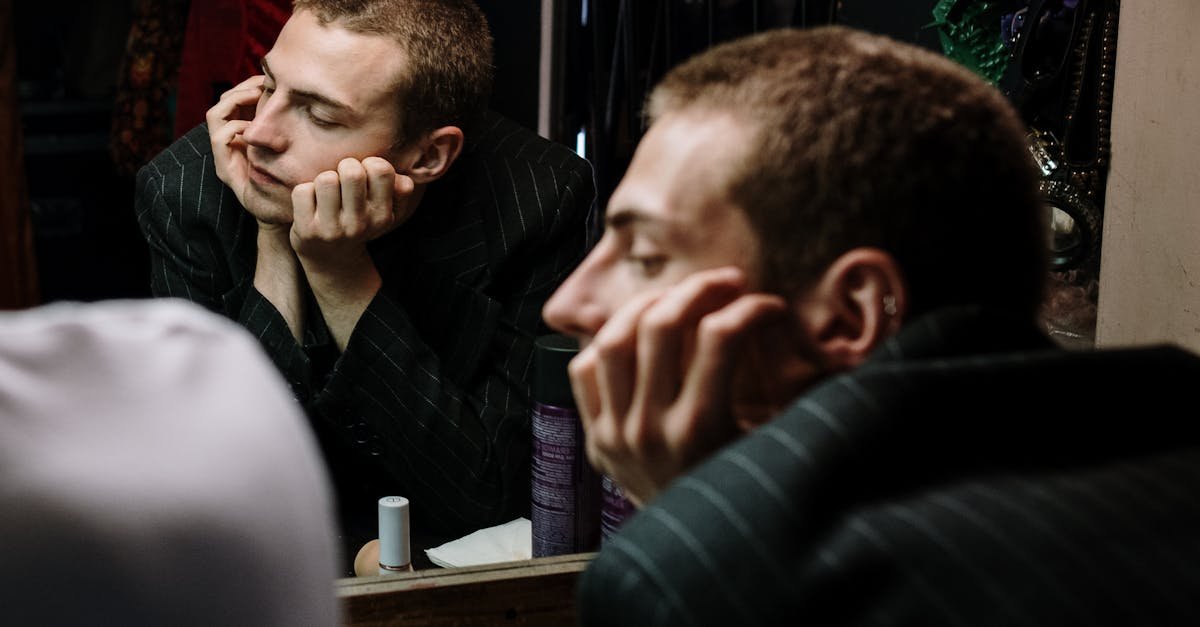 A man contemplates his reflection in a dressing room mirror, exploring identity and self-reflection.