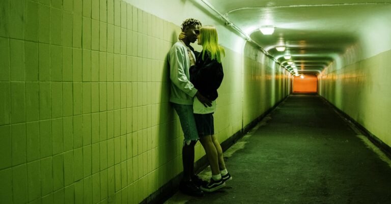 Couple embracing in a fluorescent lit tunnel, creating an urban and passionate scene.