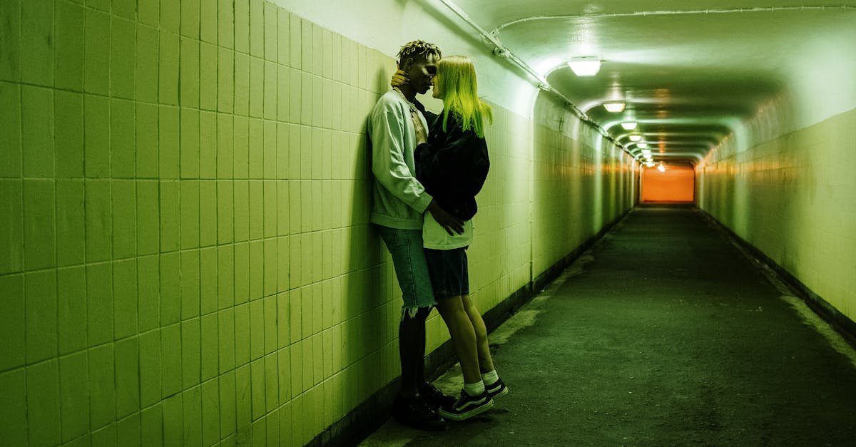 Couple embracing in a fluorescent lit tunnel, creating an urban and passionate scene.