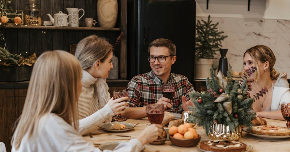 Friends enjoying a festive holiday dinner indoors with a cozy atmosphere and Christmas decorations.