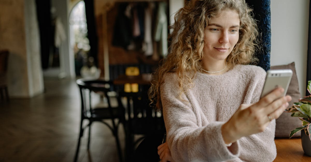 A young woman in a cozy sweater using her smartphone at home, enjoying a relaxed moment.