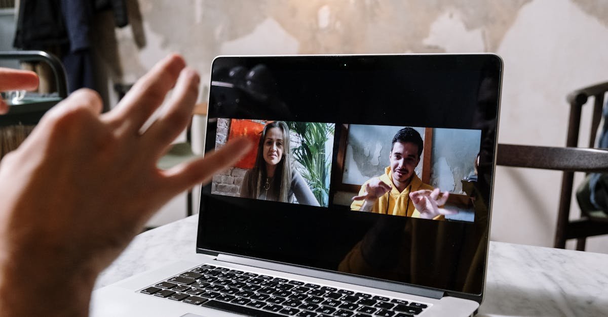 Hands gesturing during a video call on a laptop screen, showing two people in a virtual meeting.
