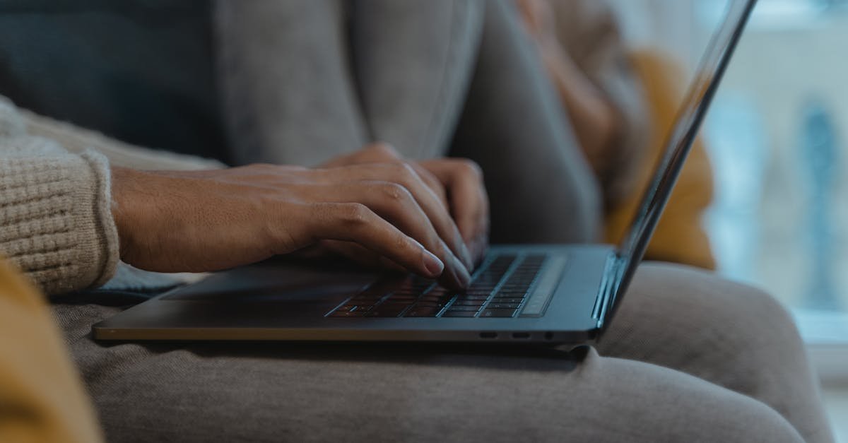 A close-up view of a person's hands typing on a laptop, capturing a cozy and modern indoor setting.