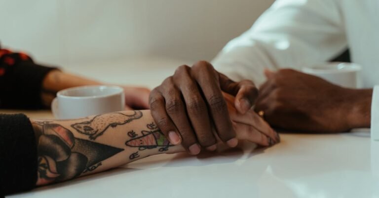 Interracial couple holding hands over coffee, showcasing love and connection with tattoos visible.