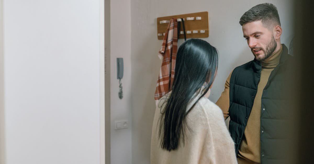 A man and woman talk inside a cozy home. They appear engaged in a conversation.