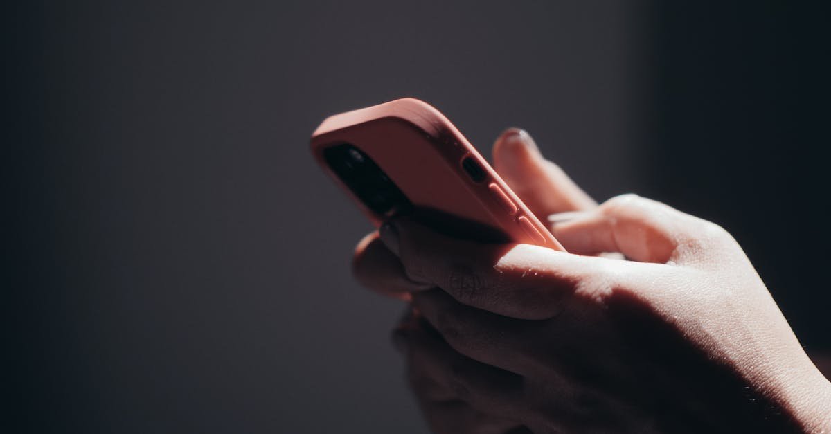 Close-up of hands holding a smartphone in dim lighting, showcasing texting or browsing activity.