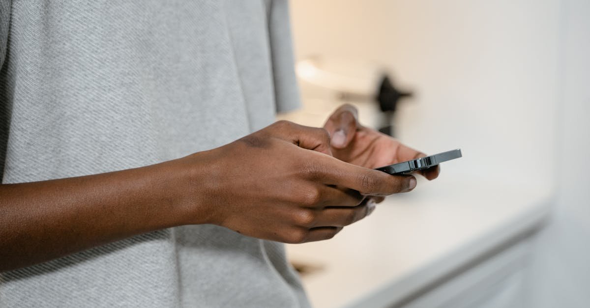 A person texting on a smartphone indoors, showing hands and device close-up.