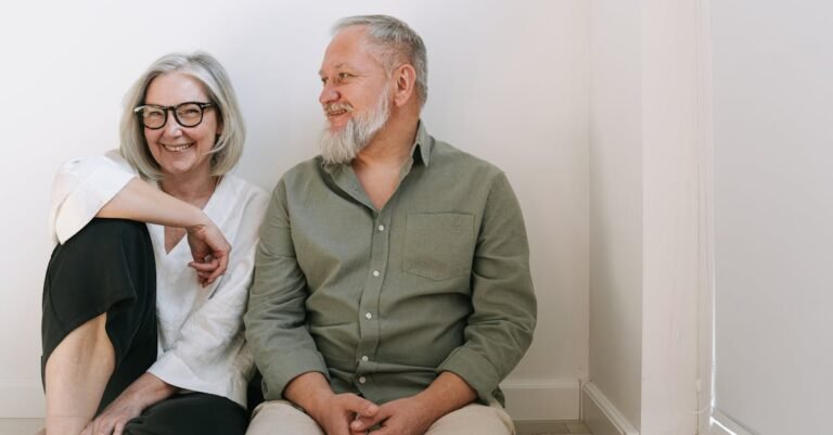 Joyful senior couple sitting together indoors, sharing smiles and love.