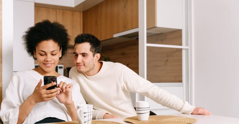 A couple sitting at a kitchen table, engaging with a mobile phone, creating a cozy family moment.