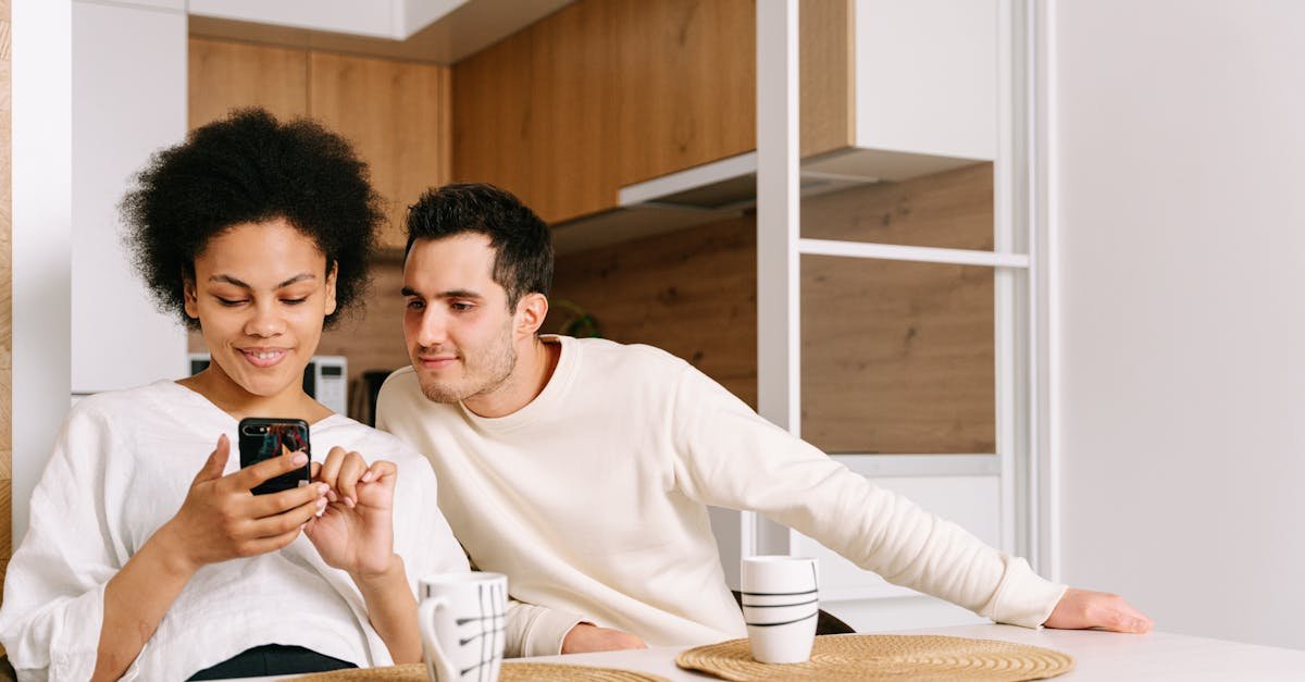 A couple sitting at a kitchen table, engaging with a mobile phone, creating a cozy family moment.