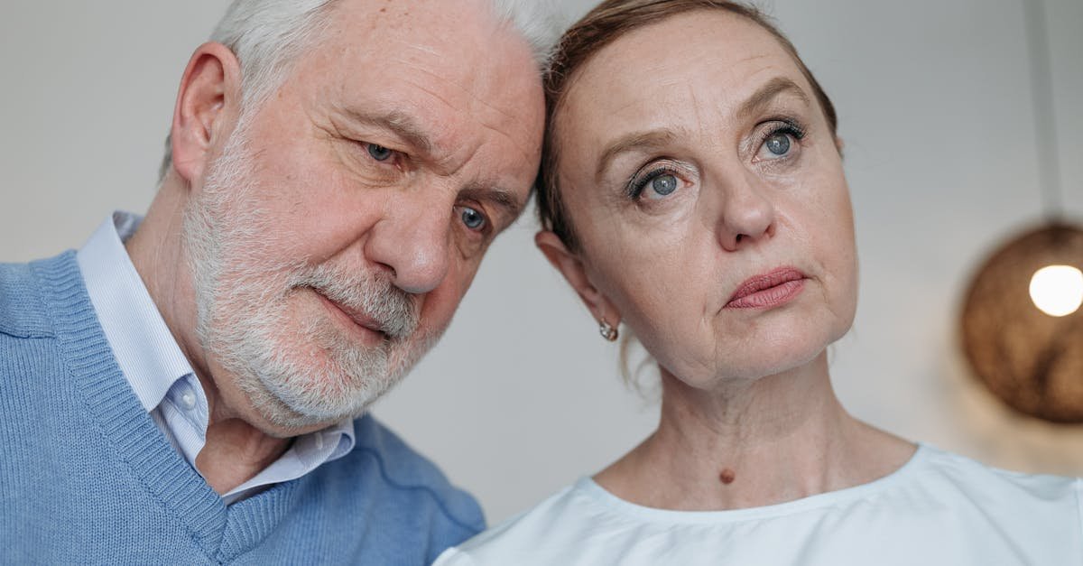 Close-up of a thoughtful elderly couple sharing a quiet moment indoors.