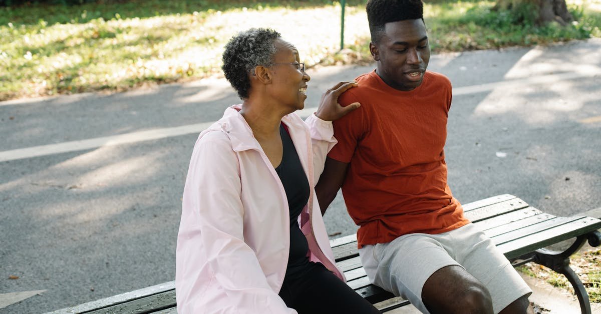 A mother and son share a moment on a park bench on a sunny day.