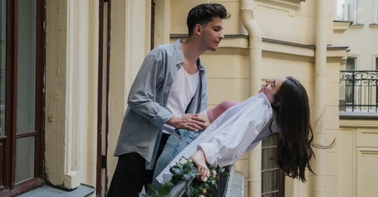 Young couple sharing a joyful moment on a balcony, capturing urban romance.